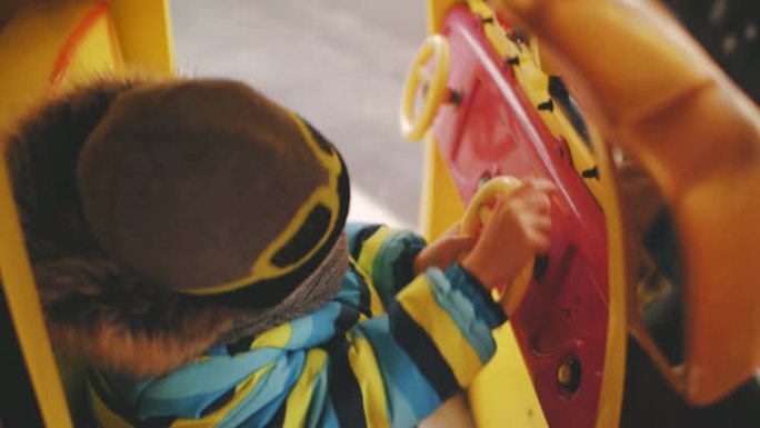 这个男孩戴着头盔在旋转木马上骑玩具车