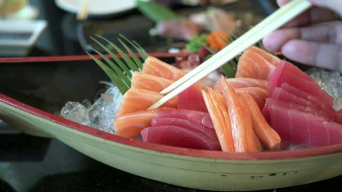 手持筷子拿新鲜鲑鱼生鱼片的前视图
