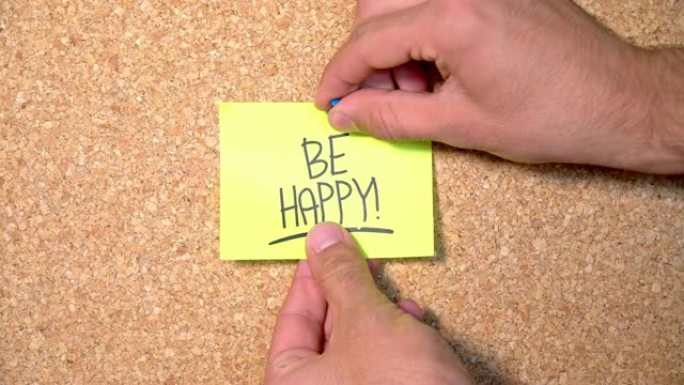 在一个男人钉在软木板上的纸上快乐单词组