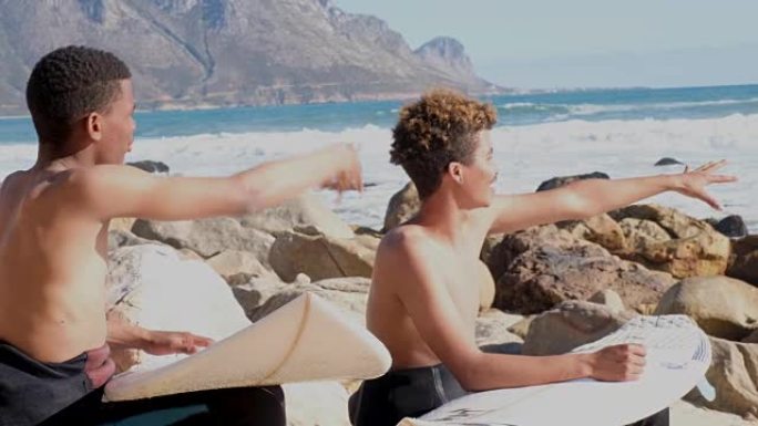 年轻的非洲男性坐在冲浪板上的岩石上