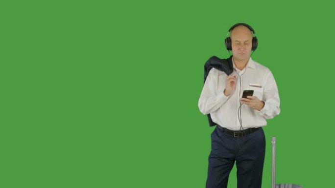 快乐的高加索商人在听智能手机中的音乐时跳舞。阿尔法通道，键控绿色屏幕