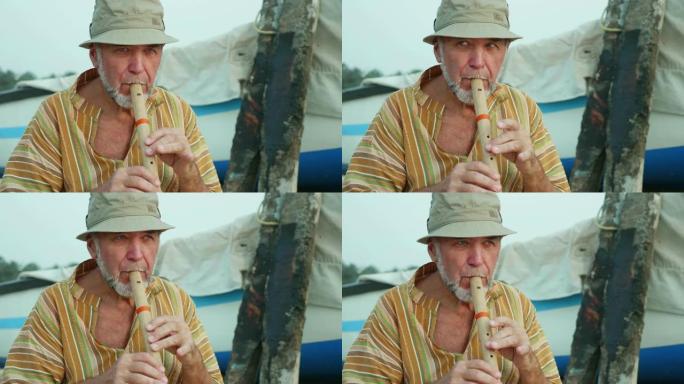 渔船旁的沙滩上玩竹笛的老人肖像