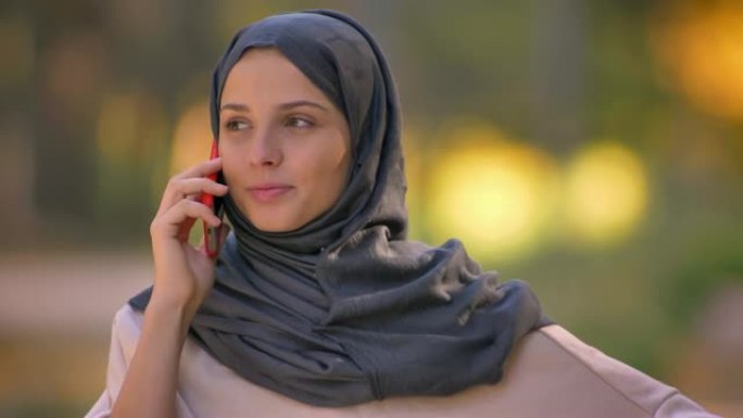 盖头穆斯林女孩的特写肖像在手机上聊天