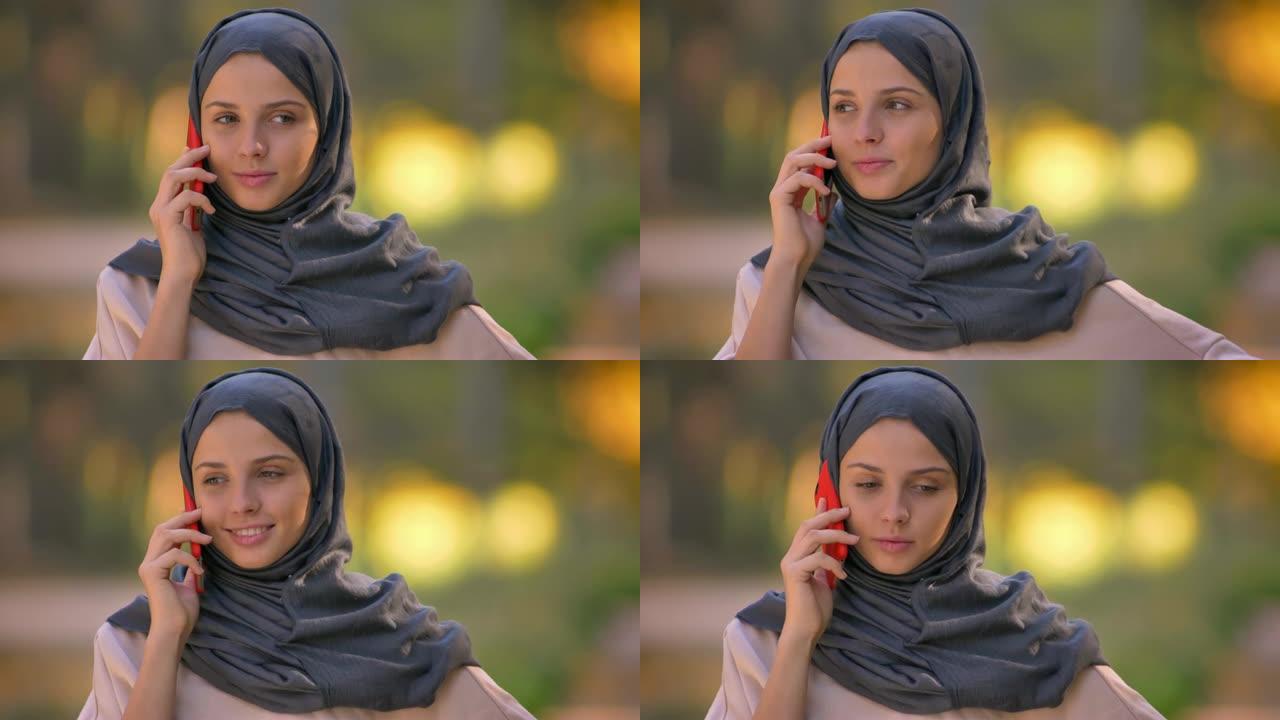 盖头穆斯林女孩的特写肖像在手机上聊天
