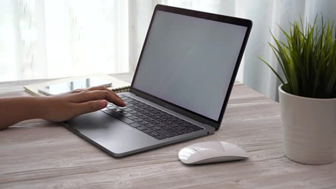 年轻女子在家工作时使用智能手机和笔记本电脑放在桌子上，女人的手使用智能手机技术，