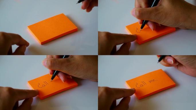 在橙色的纸上或记事本纸上手写 “call me” 一词。运动4k镜头