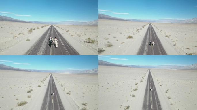 新娘和新郎在美国死亡谷的空旷沙漠路上奔跑