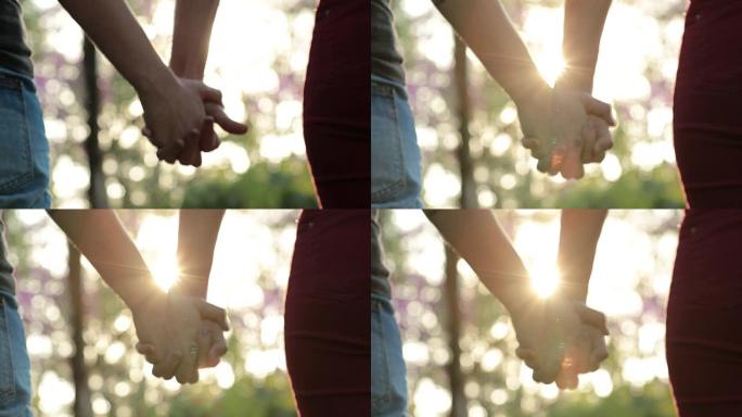 在公园里携手共进，背景是阳光耀斑。爱、感情、友谊和结合的概念
