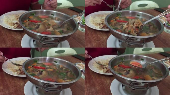 特写亚洲男子吃美味的辣炖牛尾汤