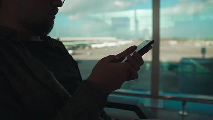 男子坐在机场的手机感应屏上滑动，特写