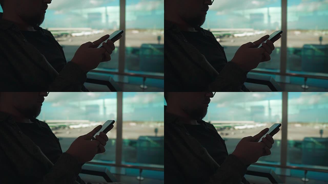 男子坐在机场的手机感应屏上滑动，特写