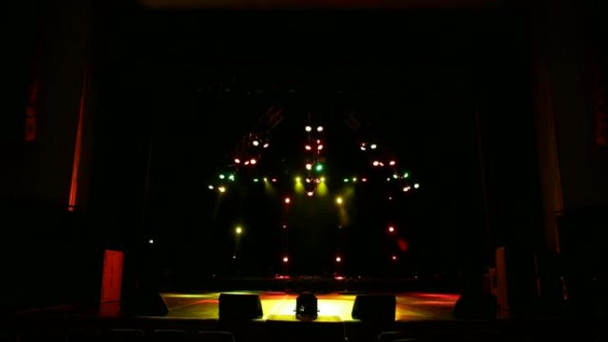 在黑暗中空荡荡的音乐会舞台上，五颜六色的聚光灯。舞台灯。