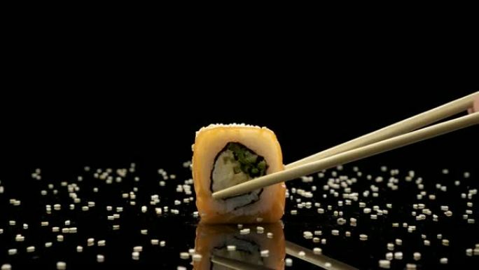 寿司卷与鲑鱼和鱼子酱在黑色背景旋转
