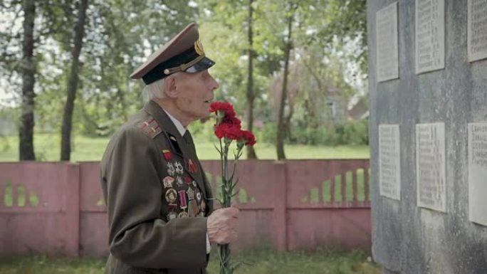 一位白发苍苍的老兵，曾参加过伟大的卫国战争和第二次世界大战，身穿制服，佩戴着许多徽章和命令，站在集体