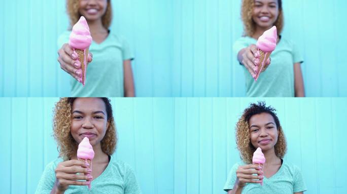快乐的黑人女孩展示粉红色融化的冰淇淋，然后开始在蓝色墙壁背景下吃它