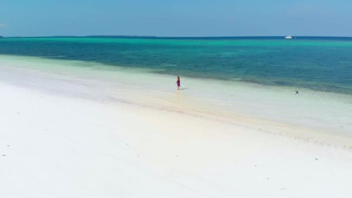 空中慢动作: 女人在热带海滩上行走，风景秀丽的绿松石水和白沙，巴西班让基岛，摩鹿加群岛，印度尼西亚，