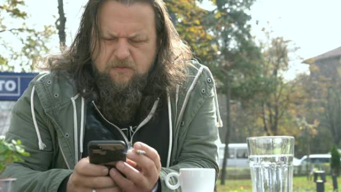 大胡子的男人在咖啡馆等着，用手机发短信