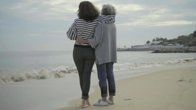 两个微笑的女人在海边拥抱。