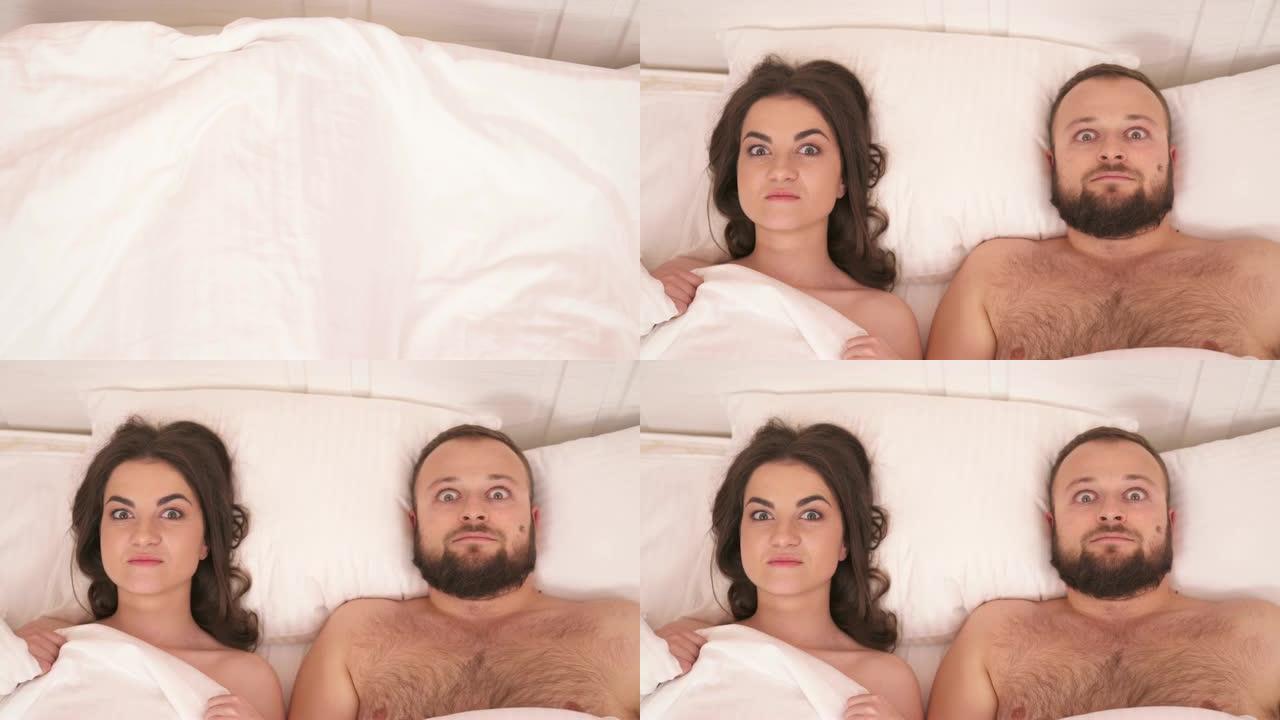 一张被带走的床上白色毯子的俯视图，一个漂亮的黑发女人，一个大胡子的男人躺在床上，瞪着眼睛，凝视着他们