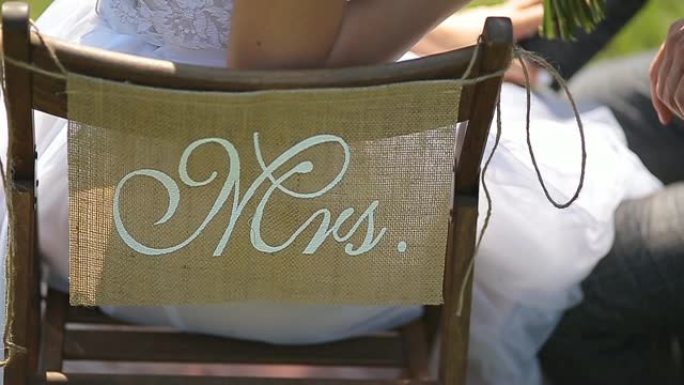 新娘和新郎坐在椅子上，上面写着先生和夫人。