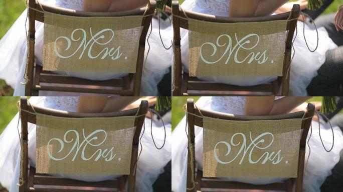 新娘和新郎坐在椅子上，上面写着先生和夫人。