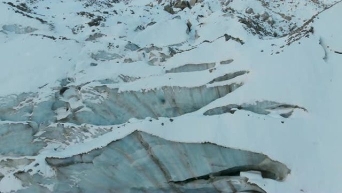 鸟瞰图特写边缘流动的冰川覆盖着高山上的雪和石头。冰川融化的自然破坏和全球变暖