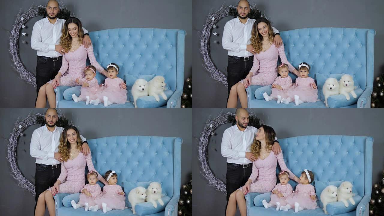 圣诞气氛，父亲和母亲和女儿在蓝色沙发上与两只小狗合影