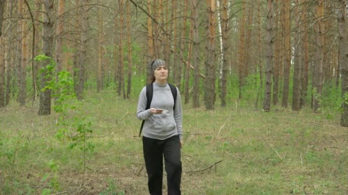 背着背包的女人穿过森林。前视图