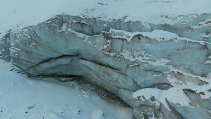 鸟瞰图特写边缘流动的冰川覆盖着高山上的雪和石头。冰川融化的自然破坏和全球变暖