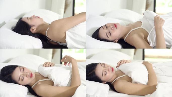 美丽的亚洲年轻女子躺在床上，头靠在枕头上舒适快乐地移动平移相机。女孩以放松为健康理念，慢动作。