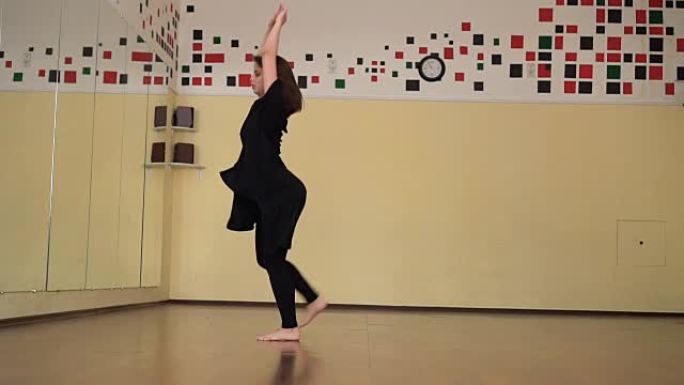 一位身穿黑衣的职业舞女在大型训练馆跳舞