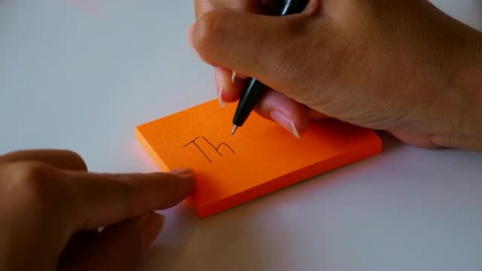 在橙色的便签纸或记事本纸上手写 “谢谢” 一词。运动4k镜头