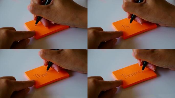 在橙色的便签纸或记事本纸上手写 “谢谢” 一词。运动4k镜头