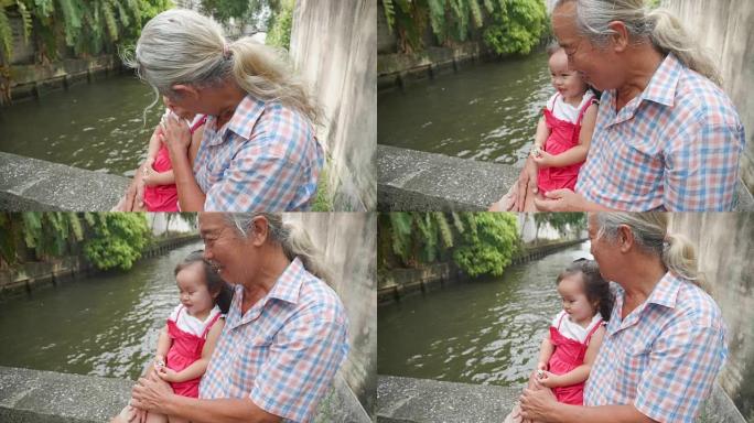 快乐的亚洲女婴肖像，高级男子坐在运河旁，感受着爱。