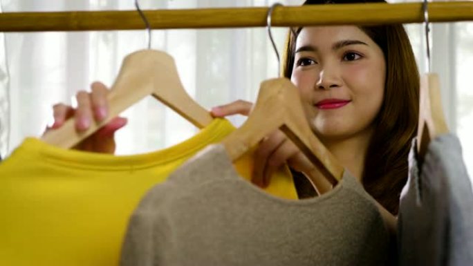 年轻美丽的亚洲女人在家里的衣柜里寻找衣服