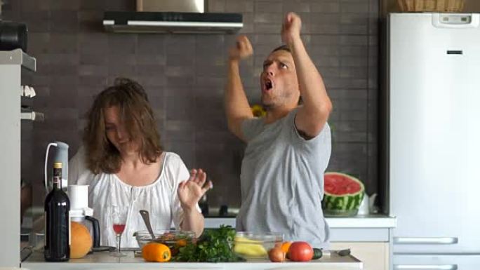 年轻顽皮的夫妇在厨房里疯狂跳舞。丈夫生妻子的气。愚人节，家庭日
