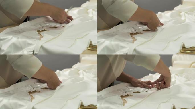 女性双手握着剪刀，按照图案剪掉花边。婚礼服装制作。