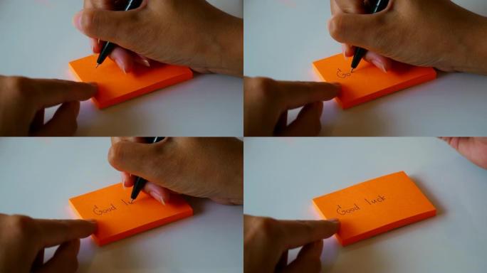 在橙色的便签纸或记事本纸上手写 “好运” 一词。运动4k镜头