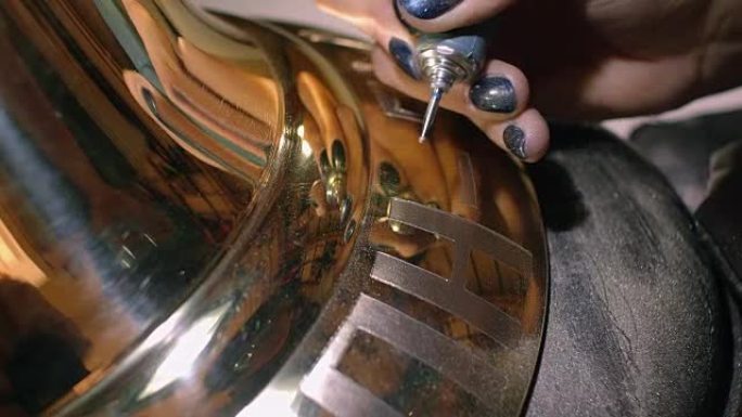雕刻师用钻头将铭文涂在铃铛上。