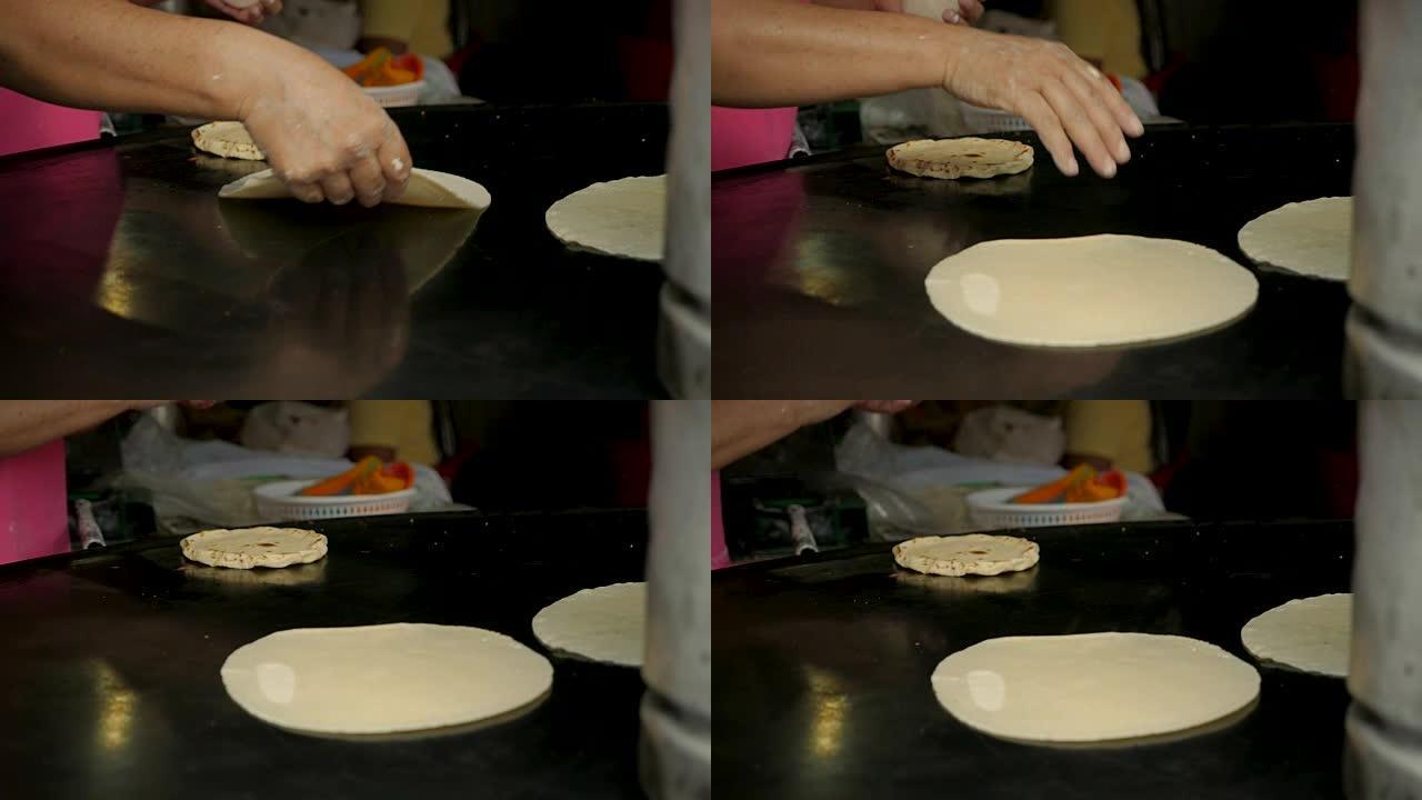 一个女人的手在金属锅上翻转手工玉米饼的特写镜头