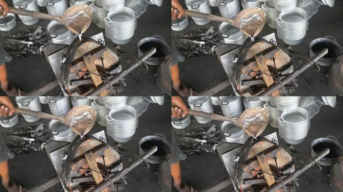 工人正在将液态铝倒入制作锅的模具中 (特写)