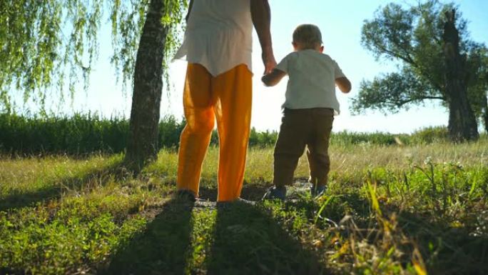 可爱的男孩在阳光明媚的夏日和父亲一起穿过绿色公园时在草地上发现了一些东西。年轻的爸爸和小儿子在户外共