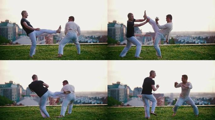 体格健壮的男人展示巴西舞蹈卡波耶拉，在草地上打架有趣，微笑