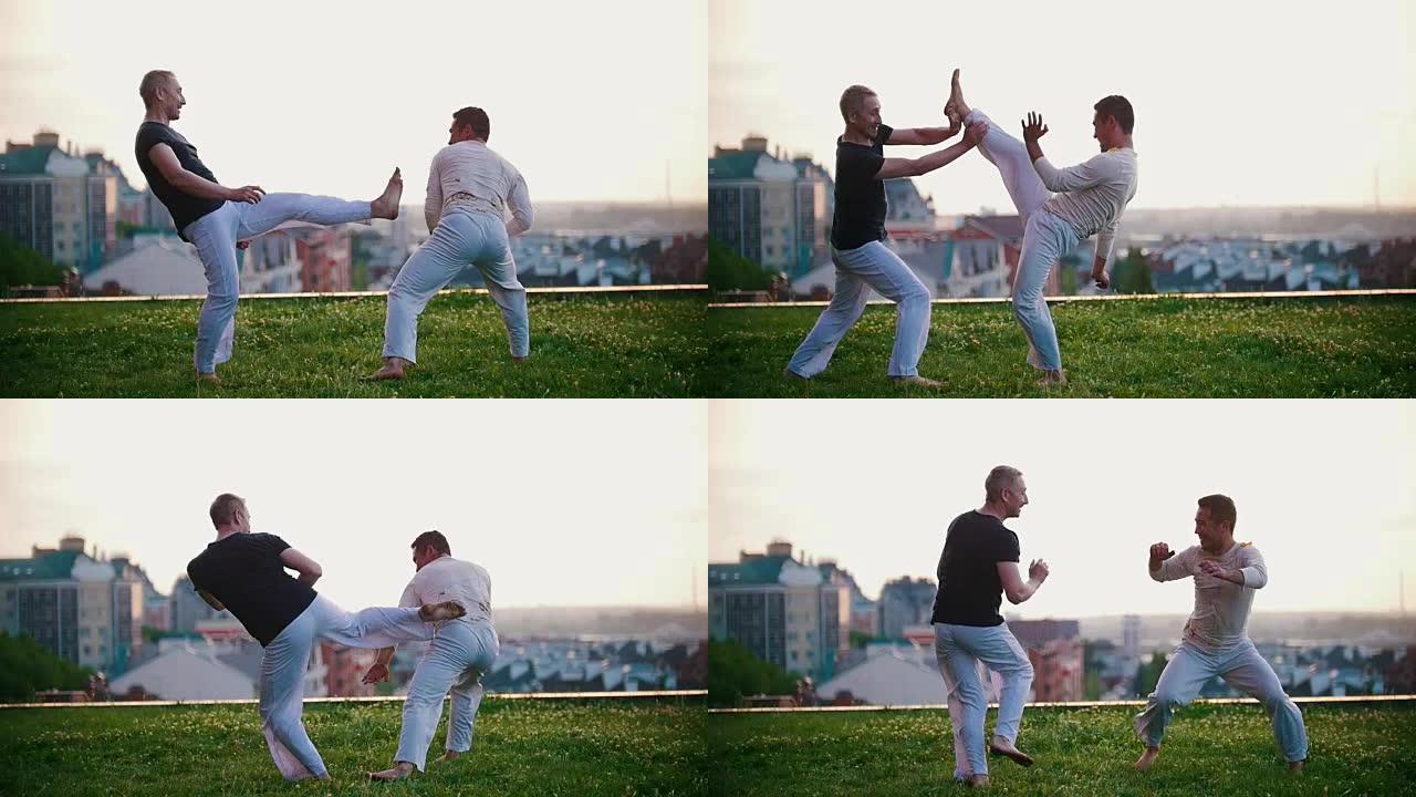 体格健壮的男人展示巴西舞蹈卡波耶拉，在草地上打架有趣，微笑