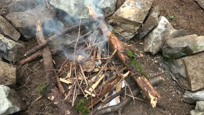 将小而干燥的材料放在森林里壁炉的火上
