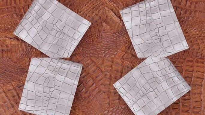 旋转，两个纹理鳄鱼皮，灰色皮革钱包躺在棕色皮肤上。特写。