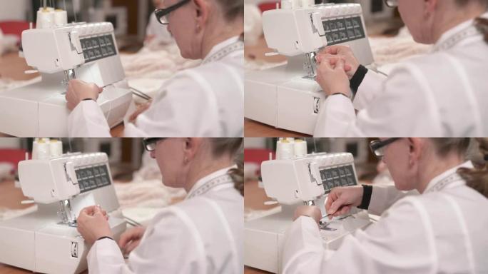 裁缝准备缝纫机缝制的特写镜头。她把线穿过针眼，然后用剪刀剪断。