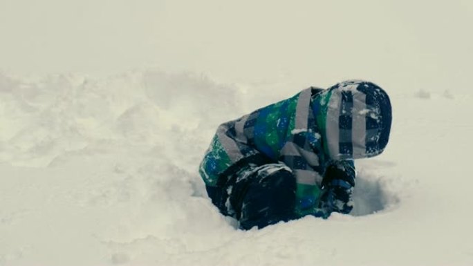 男孩在雪地上挖了一个洞，然后爬上去。