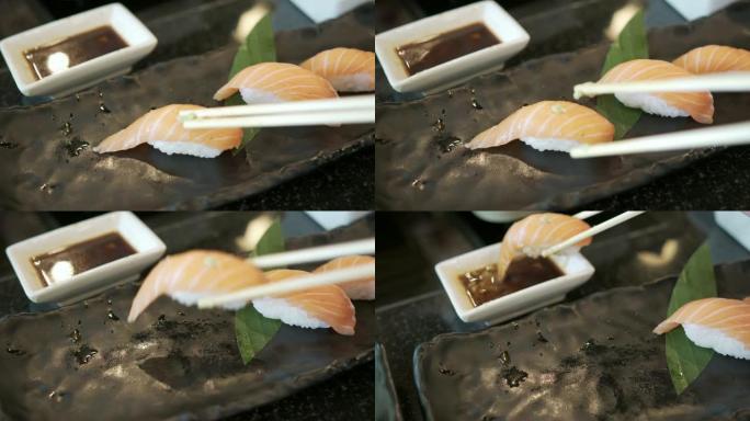 手持筷子拿新鲜三文鱼寿司的前视图