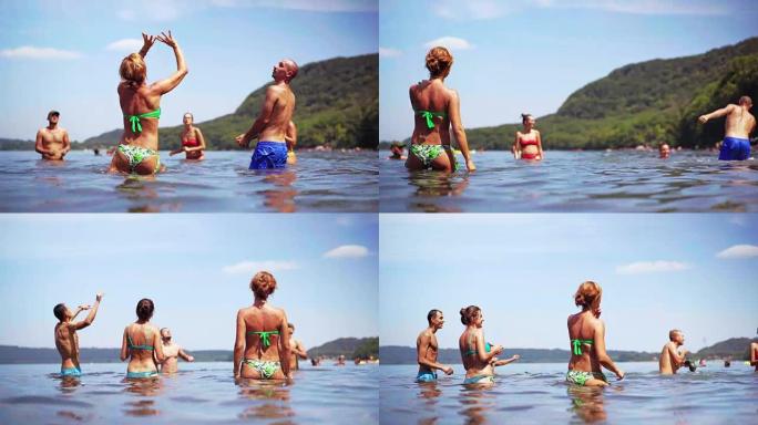 美丽和快乐的青少年朋友在暑假在水中的海滩上玩得开心，他们跳起来玩沙滩排球。一群年轻漂亮的人在海滩上玩